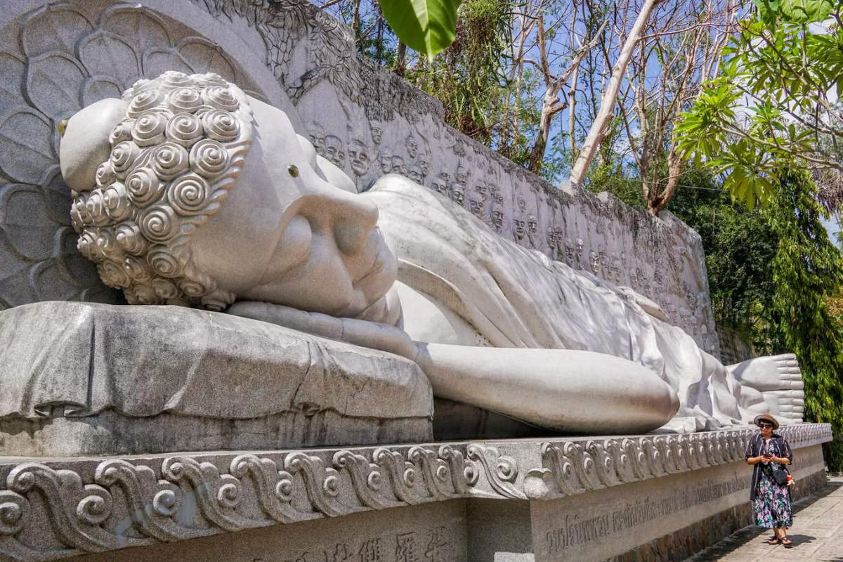 Lying Buddha statue with 49 disciples depicted in the background at Long Son Pagoda